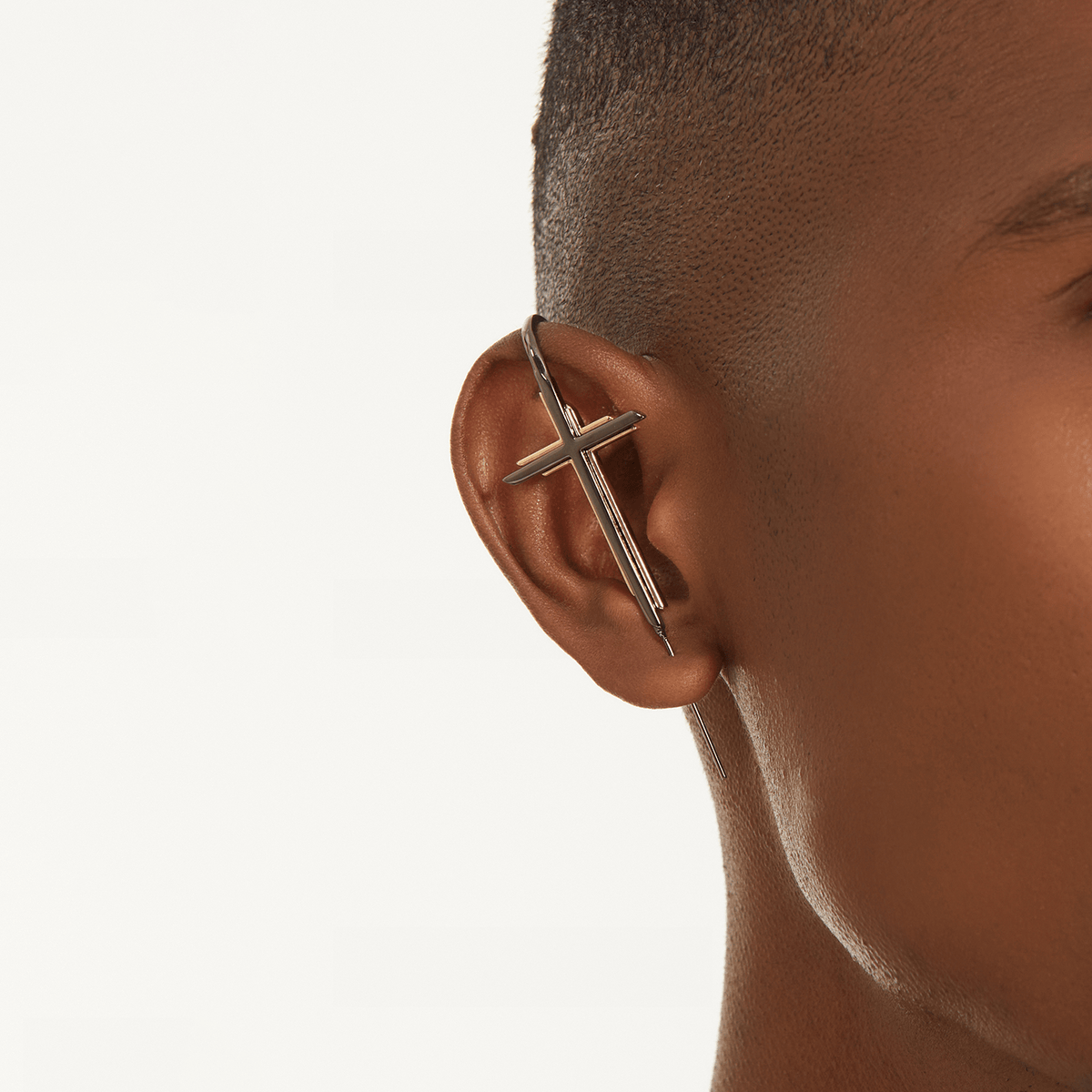 Cross ear cuff in black worn on the ear, profile view