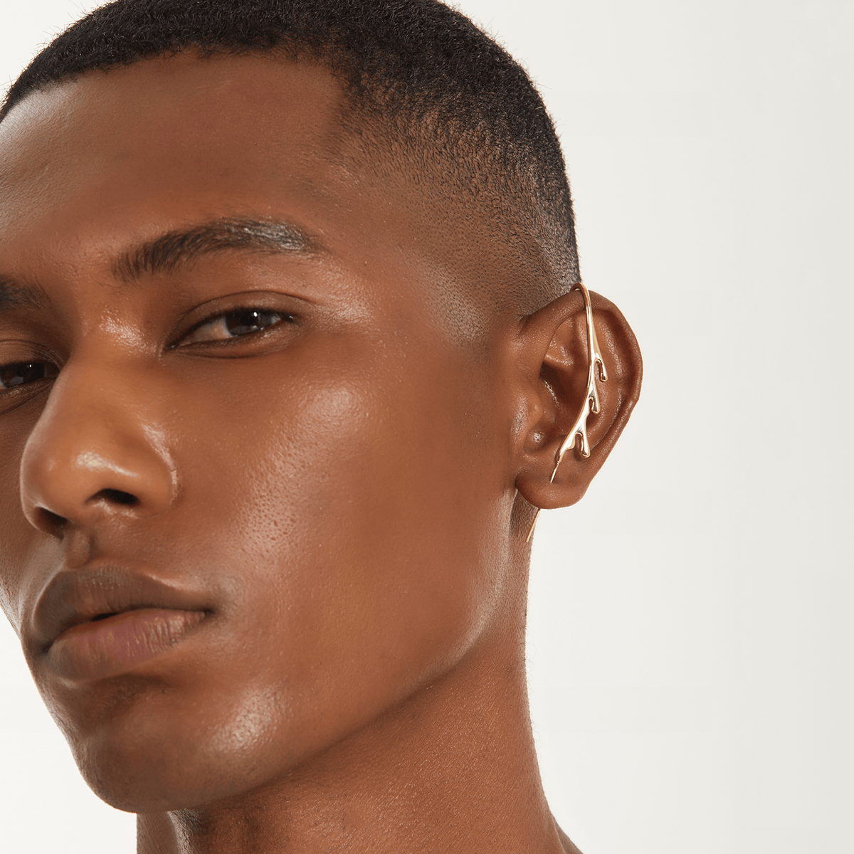 Drip ear cuff in gold worn on the ear, profile view