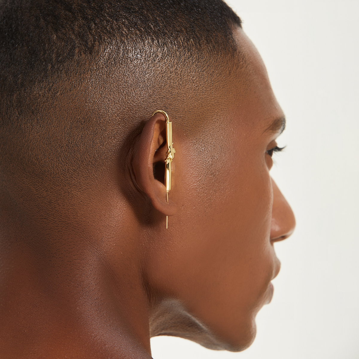Helping Hand ear cuff in gold worn on the ear, profile view
