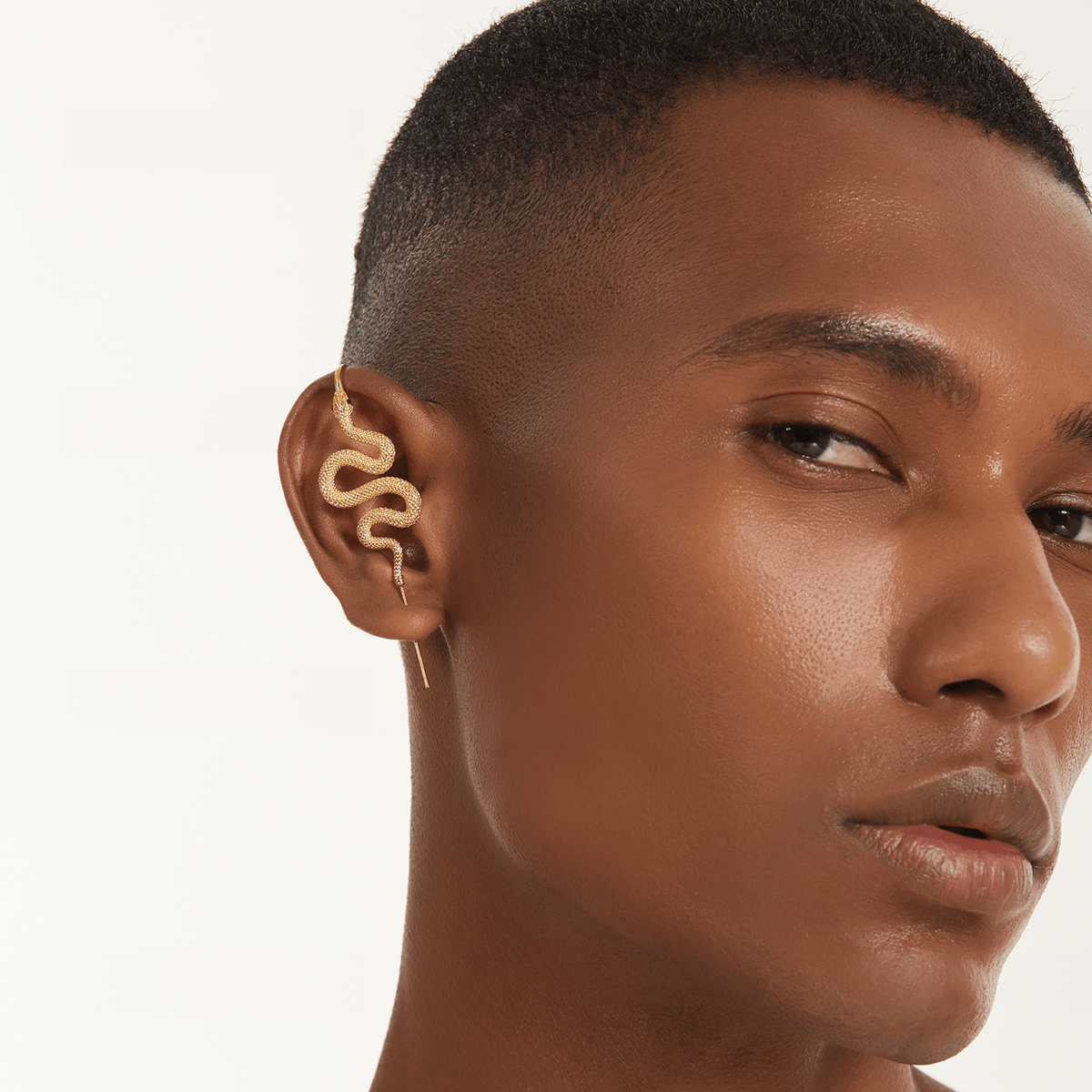 Serpent ear cuff in gold worn on the ear, profile view