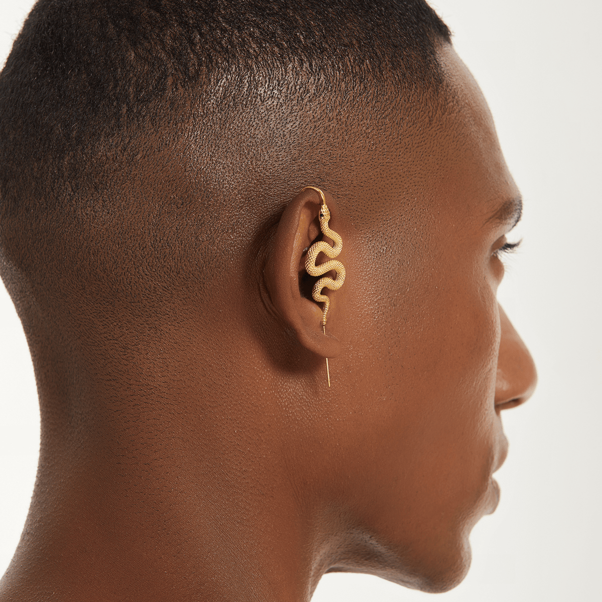 Serpent ear cuff in gold worn on the ear, profile view