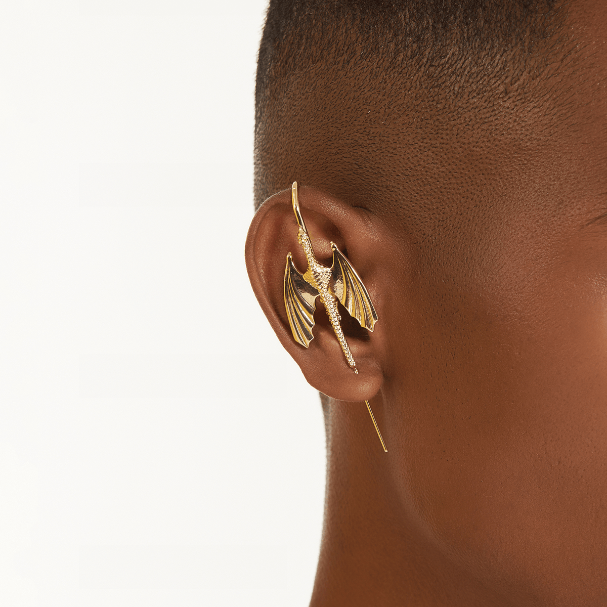 Stormscale ear cuff in gold worn on the ear, profile view