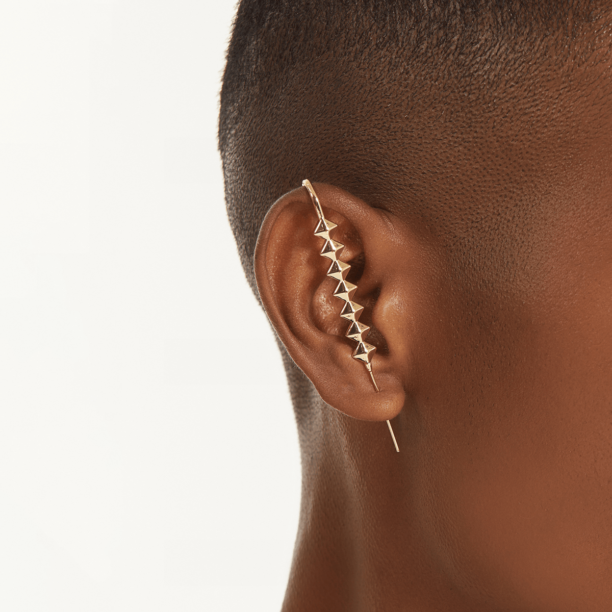 Studded ear cuff in gold worn on the ear, profile view
