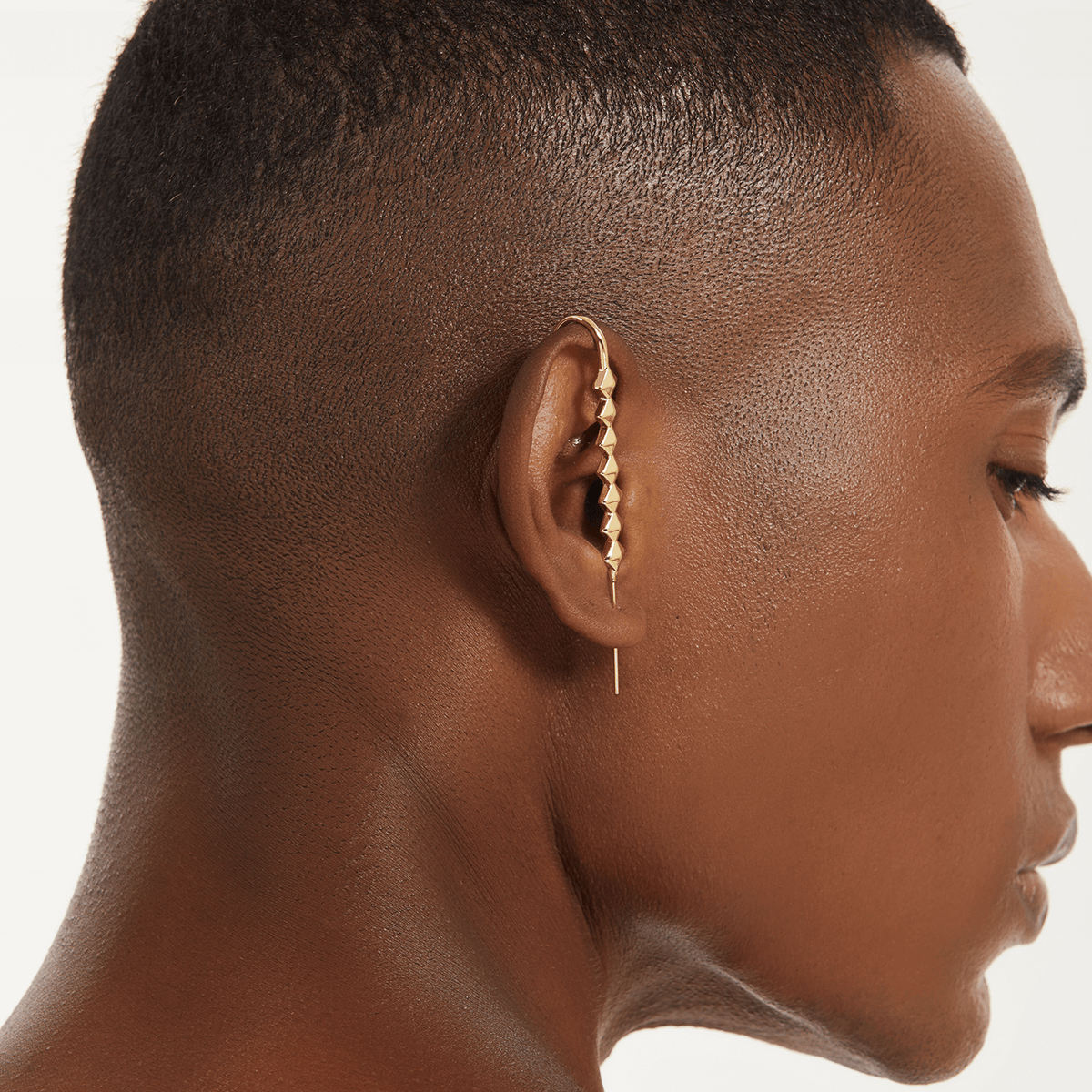Studded ear cuff in gold worn on the ear, profile view