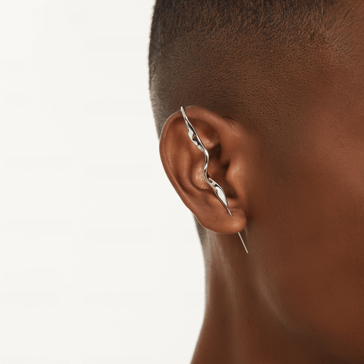 Twisted ear cuff in silver worn on the ear, profile view