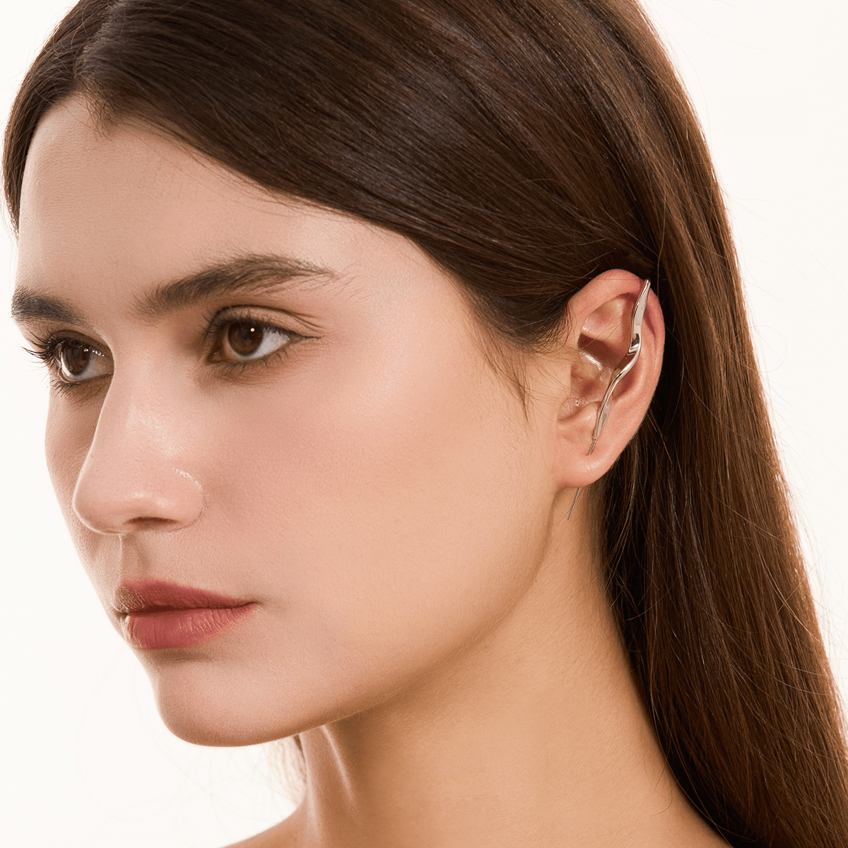 Twisted ear cuff in silver worn on the ear, profile view